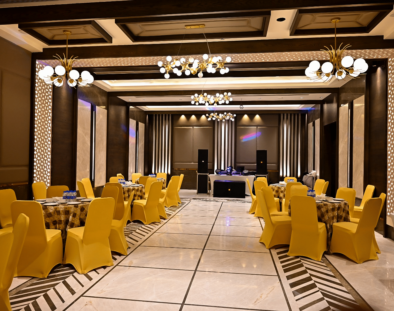 Event space with round tables and chairs arranged, featuring fancy lights hanging from the ceiling at BluSalzz Residence, Amritsar